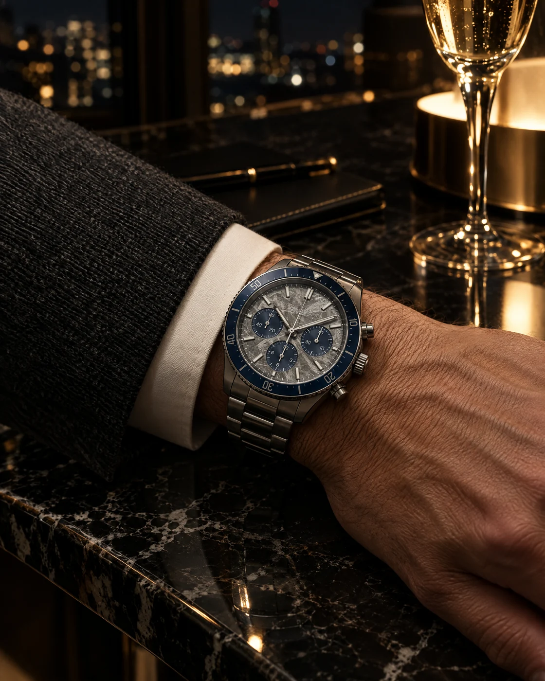 Lunaris on the wrist at night, beside a glass of champagne